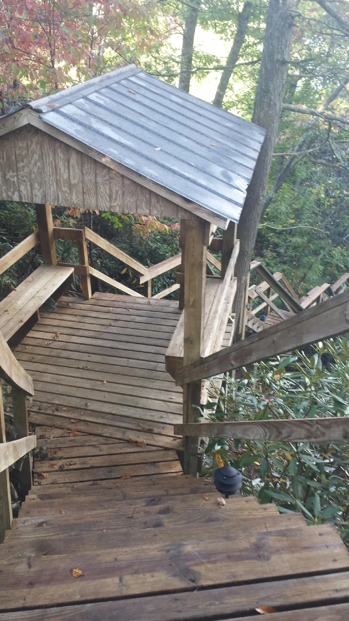 Metal roofed shelter over wooden steps on a wooded walkway — Skylight Repair & Installation work by our crew in Burton